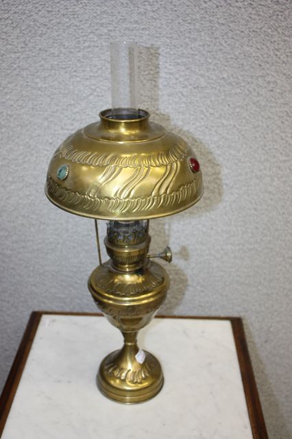 LAMPE A PETROLE EN METAL DORE ET INCRUSTATIONS DE PIERRES COLOREES. HAUT. 45 CM.
