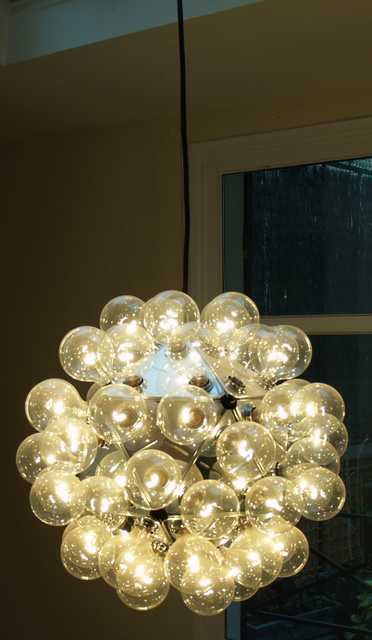 SUSPENSION A LUMIERE TARAXACUM PAR ACHILLE CASTIGLIONI, 1988. EDITEE PAR FLOS. STRUCTURE COMPOSEE DE 20 TRIANGLES EN ALUMINIUM POLI SUR LESQUELS SONT PLACES 60 AMPOULES. 80 CM DE DIAMETRE. 2 AMPOULES MANQUANTES.