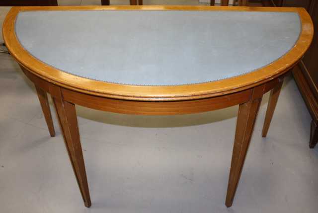 TABLE DE FORME DEMI LUNE EN BOIS NATUREL, PLATEAU RECOUVERT DE CUIR BLEU, PIEDS GAINE. DIM : 75x130x65 CM.