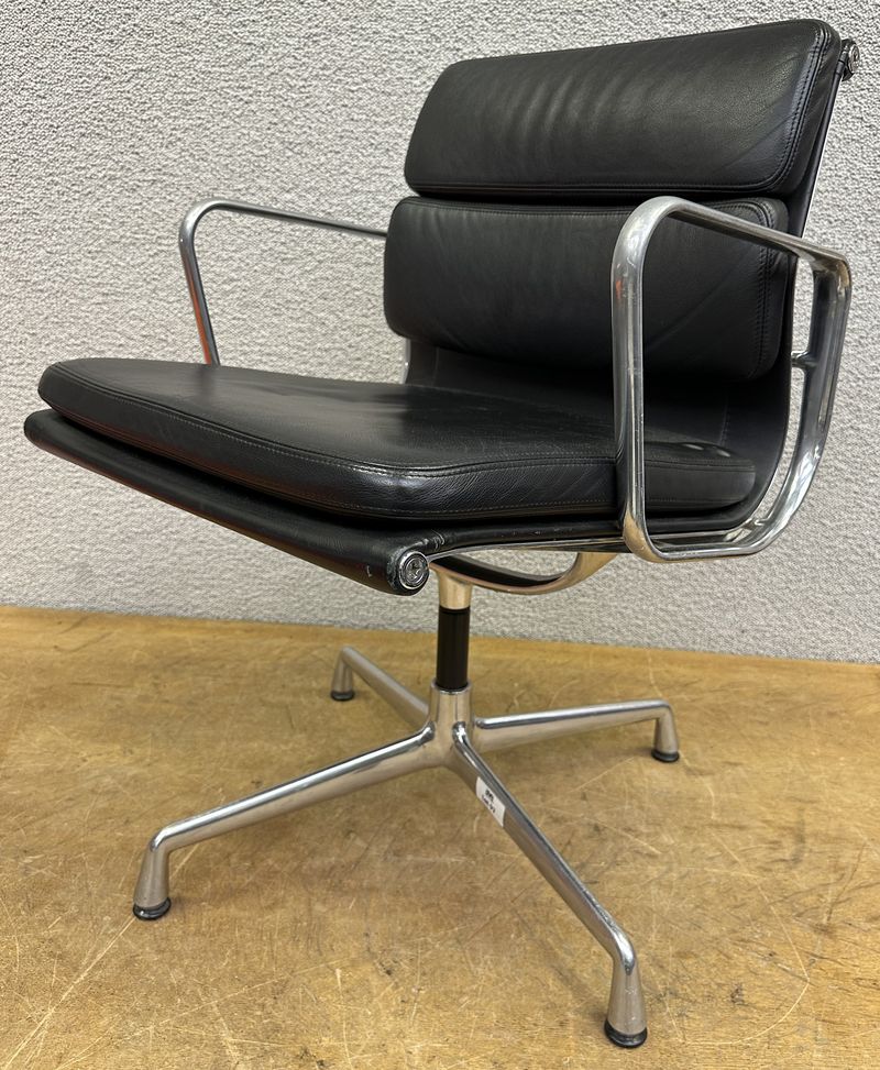 FAUTEUIL PIVOTANT DESIGN CHARLES ET RAY EAMES MODELE SOFT PAD EA208 EDITION VITRA, STRUCTURE EN ALUMINIUM, GARNITURE EN CUIR NOIR REPOSANT SUR UN PIETEMENT EN ETOILE A 4 BRANCHES SUR PATINS. USURES ET TACHE. 84 X 58 X 69 CM.