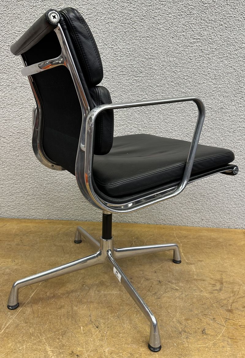 FAUTEUIL PIVOTANT DESIGN CHARLES ET RAY EAMES MODELE SOFT PAD EA208 EDITION VITRA, STRUCTURE EN ALUMINIUM, GARNITURE EN CUIR NOIR REPOSANT SUR UN PIETEMENT EN ETOILE A 4 BRANCHES SUR PATINS. USURES ET TACHE. 84 X 58 X 69 CM.