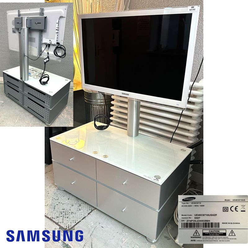 TELEVISION CONNECTEE A ECRAN LED FHD DE 40 POUCES DE MARQUE SAMSUNG MODELE UE40C6710US REPOSANT SUR UN MEUBLE A SUPPORT ECRAN EN INOX BROSSE STRUCTURE EN BOIS MDF LAQUE GRIS, PLATEAU EN VERRE OPALINE DE COULEUR BLANCHE OUVRANT PAR 4 CASIERS DE RANGEMENT A CLAPETS. VENDU AVEC TELECOMMANDE, CABLE D'ALIMENTATION, RJ45, COAXIAL ET VIDEO. DIMENSIONS TOTALES : 145 X 101 X 55 CM.