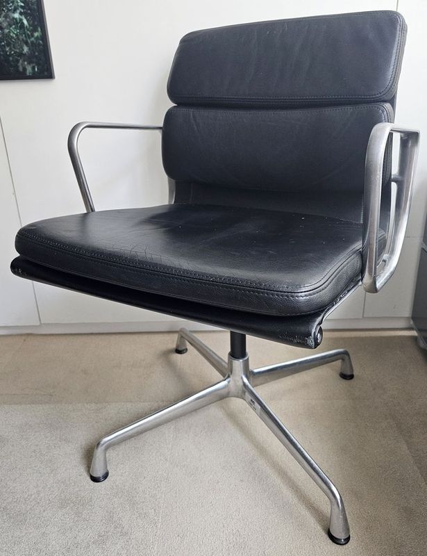 FAUTEUIL PIVOTANT DESIGN CHARLES ET RAY EAMES MODELE SOFT PAD EA208 EDITION VITRA, STRUCTURE EN ALUMINIUM, GARNITURE EN CUIR NOIR REPOSANT SUR UN PIETEMENT EN ETOILE A 4 BRANCHES SUR PATINS. 84 X 58 X 69 CM. TRES LEGERE USURE CUIR ET ALUMINIUM.