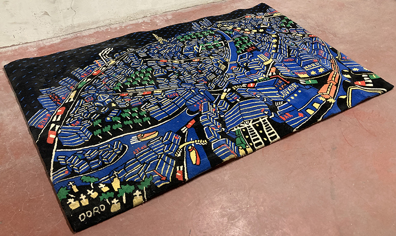 TAPIS DE MARQUE TISCA EN LAINE A FOND DE COULEUR NOIRE A MOTIF DUNE SCENE DE LA VILLE DE PARIS NOCTURNE. SIGNE BAS A GAUCHE "DORO". 209 X 130 CM. ARCUEIL SOUS-SOL POSTE