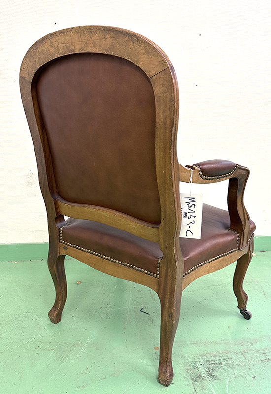 FAUTEUIL DE STYLE LOUIS XV, DOSSIER, ASSISE ET ACCOUDOIRS EN CUIR CLOUTE DE COULEUR FAUVE REPOSANT SUR UNE STRUCTURE ET 4 PIEDS EN CHENE SCULPTE AVEC ROULETTES. 85 X 68 X 63 CM. ARCUEIL 3 0014. LOCALISATION : ARCUEIL RESERVE 00 SALLE 14