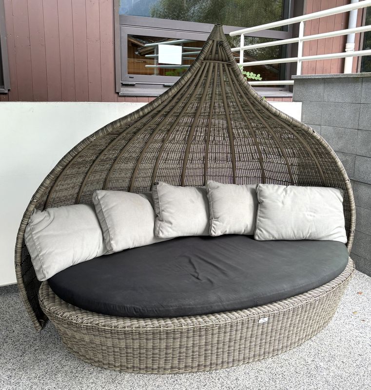 ESPACE DE DETENTE OU CANAPE ALCOVE EN FORME DE NID DE COLIBRI EN OSIER ARTIFICIEL COMPRENANT UNE PARTIE ARRIERE COUPE VENT AMOVIBLE ET UNE ASSISE DE FORME OVALE, ASSISE GALETTE EN TISSU DE COULEUR NOIR (DECHIRURE ET INSOLATION). ON Y JOINT 5 COUSSINS EN TISSU DE COULEUR TAUPE. 183 X 230 X 130 CM.