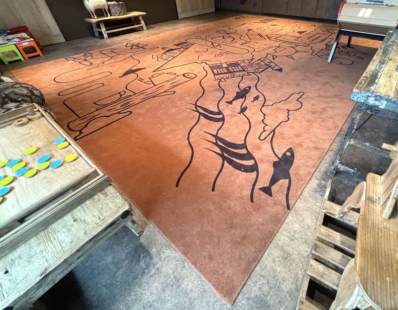 TAPIS EN LAINE A MOTIFS ET PERSONNAGES SUR UN FOND DE COULEUR CORAIL. 490 X 670 CM.