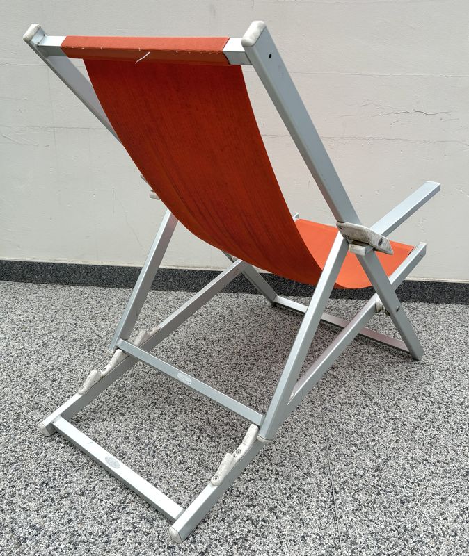 X17 CHILIENNE OU TRANSAT OU CHAISE LONGUE EN ALUMINIUM ANODISE DE COULEUR GRIS ET TISSUS TENDU DE COULEUR ORANGE DE MARQUE ROLAND VLAEMYNCK MODELE ALPINA. 103.5 X 65.5 X 106 CM.