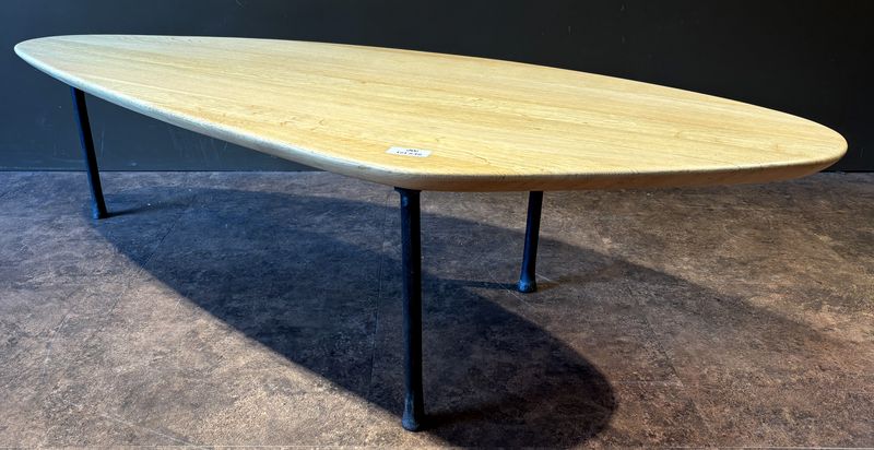 TABLE BASSE DANS LE GOUT SCANDINAVE DES ANNEES 1950 DE MARQUE CARAVANE MODELE YOMI, PLATEAU DE FORME OVOIDE EN CHENE NATUREL REPOSANT SUR 3 PIEDS EN FER FORGE. 41 X 160.5 X 62 CM.