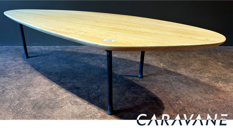 TABLE BASSE DANS LE GOUT SCANDINAVE DES ANNEES 1950 DE MARQUE CARAVANE MODELE YOMI, PLATEAU DE FORME OVOIDE EN CHENE NATUREL REPOSANT SUR 3 PIEDS EN FER FORGE. 41 X 160.5 X 62 CM.