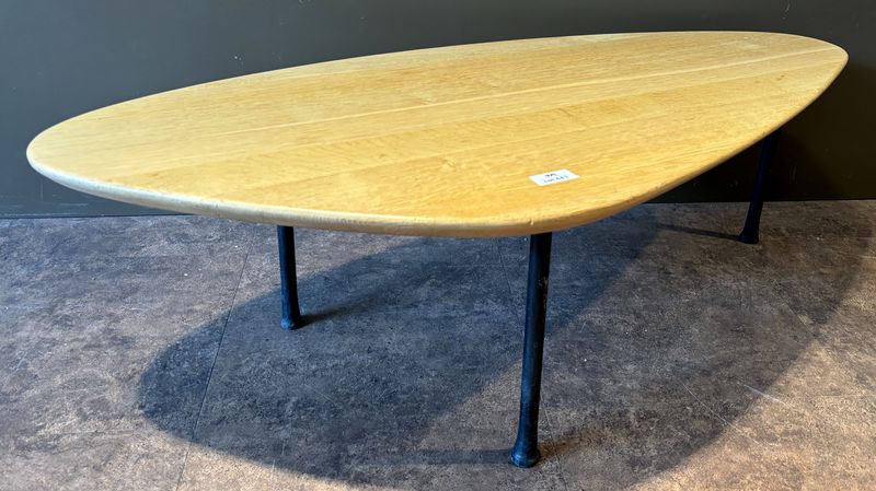 TABLE BASSE DANS LE GOUT SCANDINAVE DES ANNEES 1950 DE MARQUE CARAVANE MODELE YOMI, PLATEAU DE FORME OVOIDE EN CHENE NATUREL REPOSANT SUR 3 PIEDS EN FER FORGE. 41 X 136 X 64 CM.