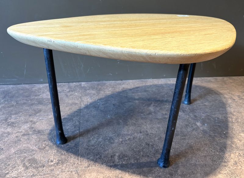 TABLE BASSE DANS LE GOUT SCANDINAVE DES ANNEES 1950 DE MARQUE CARAVANE MODELE YOMI, PLATEAU DE FORME OVOIDE EN CHENE NATUREL REPOSANT SUR 3 PIEDS EN FER FORGE. 41 X 81 X 57 CM.