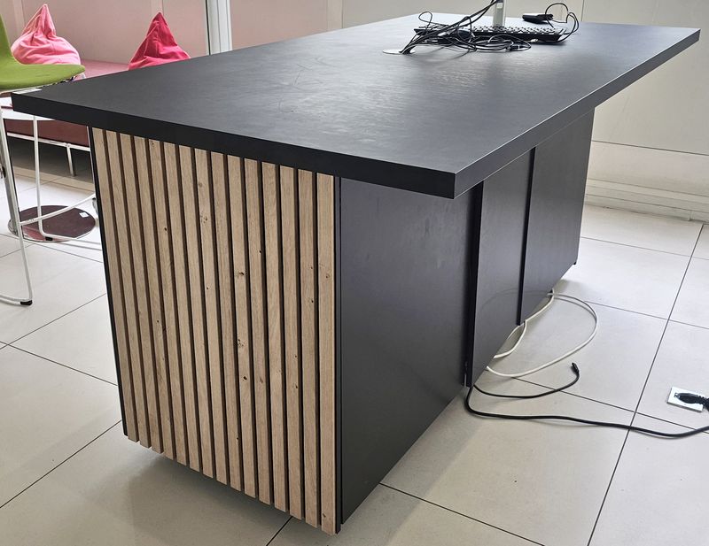 TABLE HAUTE OU COMPTOIR A PLATEAU RECTANGULAIRE EN BOIS STRATIFIE DE COULEUR NOIRE REPOSANT SUR UN CAISSON EN BOIS STRATIFIE DE COULEUR NOIRE DECORE DE LAME DE BOIS CLAIR ET D'UNE ENSEIGNE NEON "TECHBAR". 93 X 184 X 100 CM. LOCALISATION -> BAT A : ACCUEIL