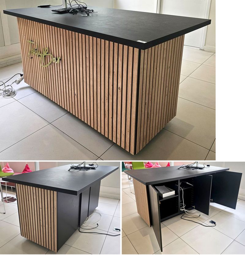 TABLE HAUTE OU COMPTOIR A PLATEAU RECTANGULAIRE EN BOIS STRATIFIE DE COULEUR NOIRE REPOSANT SUR UN CAISSON EN BOIS STRATIFIE DE COULEUR NOIRE DECORE DE LAME DE BOIS CLAIR ET D'UNE ENSEIGNE NEON "TECHBAR". 93 X 184 X 100 CM. LOCALISATION -> BAT A : ACCUEIL