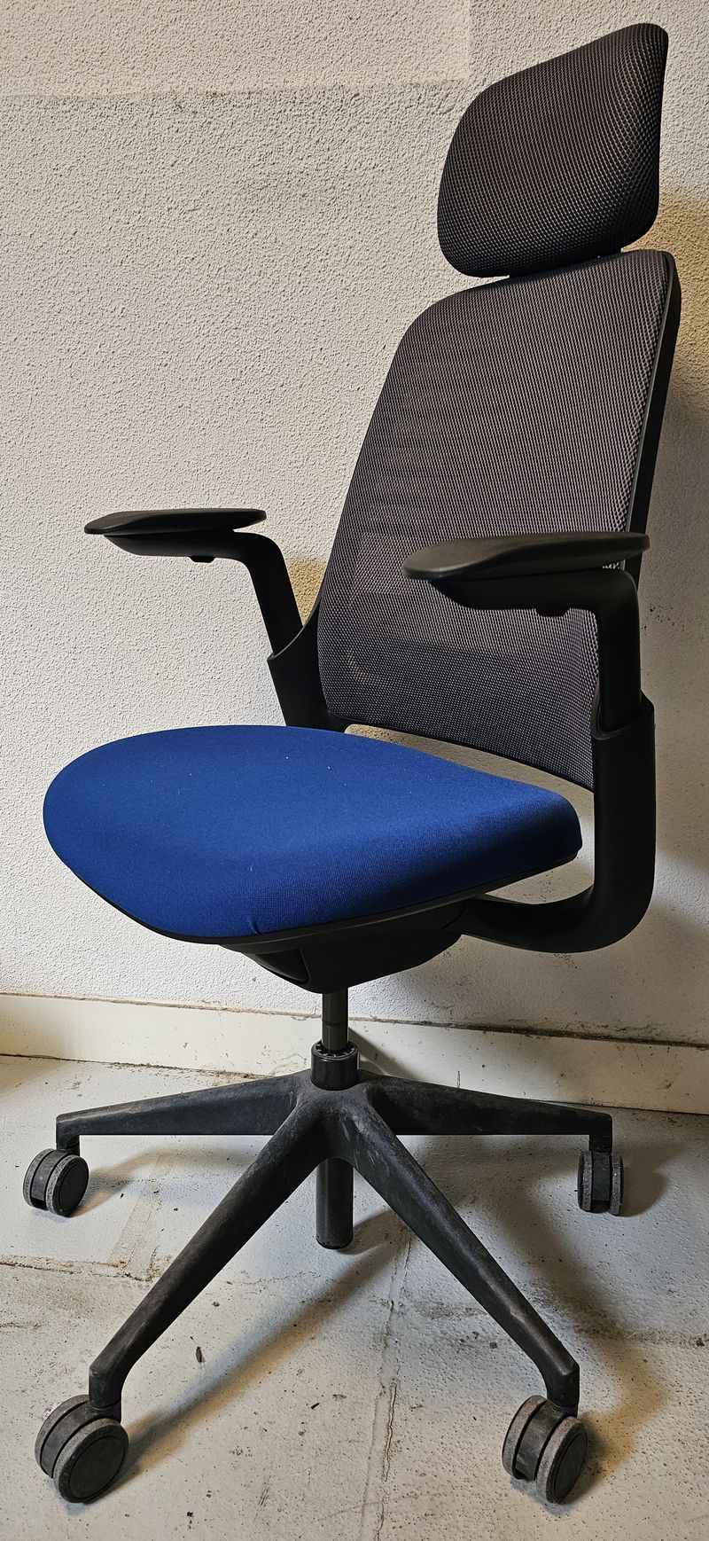 FAUTEUIL DE BUREAU A HAUTEUR AJUSTABLE ET TETIERE, SOUTIEN LOMBAIRE DE MARQUE STEELCASE MODELE SERIES 1 DOSSIER EN RESILLE DE COULEUR GRIS SOURIS, ASSISE EN TISSU DE COULEUR BLEUE ROI ET TETIERE EN TISSU DE COULEUR GRIS SOURIS REPOSANT SUR UN PIETEMENT ETOILE A ROULETTES EN ACIER LAQUE NOIR. HAUTEUR MIN : 115 CM ; HAUTEUR MAX : 126 CM ; 64 X 64 CM. 2 UNITES VENDU A L'UNITE AVEC FACULTE DE REUNION. LOCALISATION -> BAT H : RDC