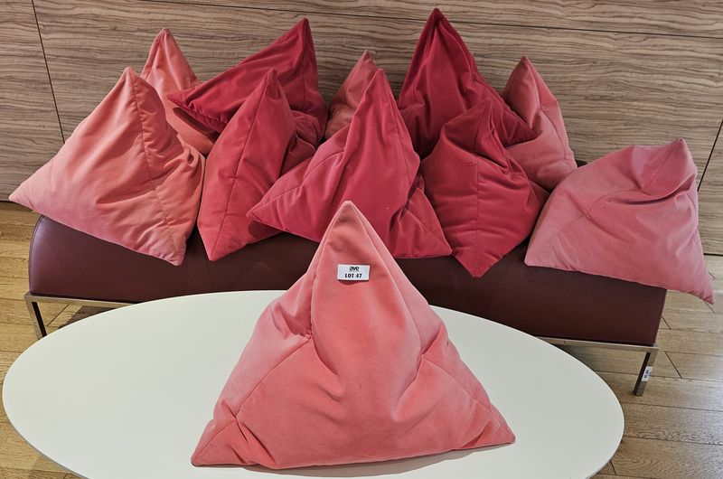 11 COUSSINS DE FORME TRIANGULAIRE EN VELOURS DE COULEUR ROSE ET ROUGE FRAMBOISE. 40 X 57 X 57 CM. LOCALISATION -> BAT A : ACCUEIL