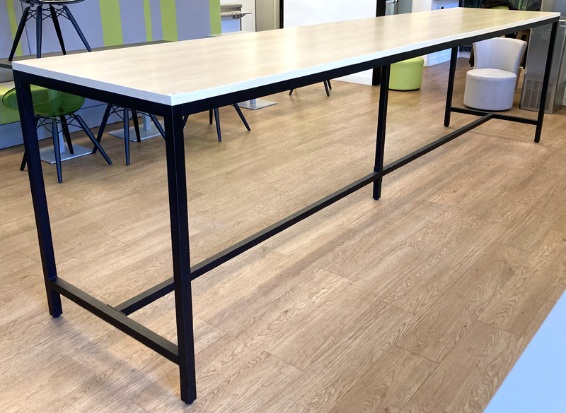 TABLE HAUTE PLATEAU RECTANGULAIRE EN BOIS STRATIFIE CLAIR REPOSANT SUR UNE STRUCTURE A 5 PIEDS AVEC REPOSE-PIEDS EN ACIER LAQUE NOIR. 113 X 420 X 90 CM. LOCALISATION -> AVE - 2 BOULEVARD DU GENERAL DE GAULLE - 92500 RUEIL MALMAISON