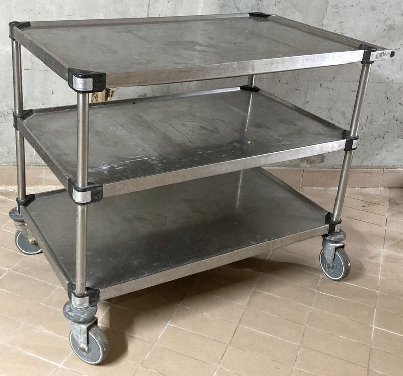 CHARIOT DE SERVICE EN INOX ALIMENTAIRE A 3 NIVEAUX AVEC 4 ROULETTES DIRECTRICES DONT 2 FREINEES. USURE. 85 X 108 X 65 CM.