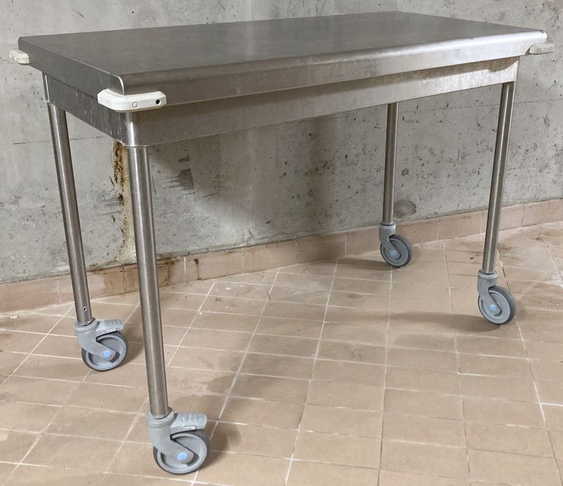 TABLE DE PREPARATION EN INOX ALIMENTAIRE REPOSANT SUR 4 PIEDS AVEC ROULETTES DIRECTIONNELLES DONT 2 FREINEES. 90 X 124 X 64 CM.