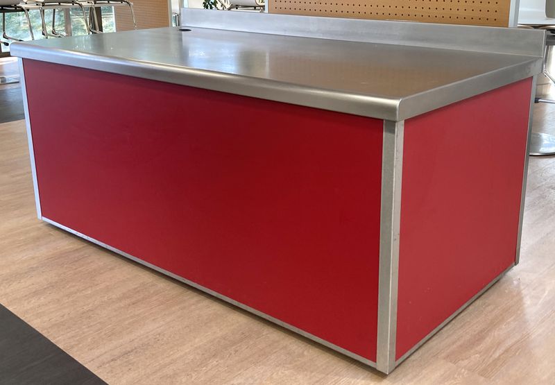 BUFFET ADOSSE DE MARQUE VAUCONSTANT EN INOX ALIMENTAIRE, VERRE ET BOIS LAQUE ROUGE PLATEAU EN INOX, AVEC TRAPPE DE SERVICE COMPRENANT 4 PRISES 230V. 96,5 X 200 X 100 CM.