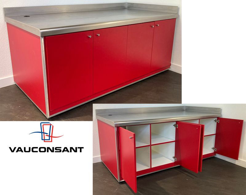 BUFFET ADOSSE DE MARQUE VAUCONSTANT EN INOX ALIMENTAIRE, VERRE ET BOIS LAQUE ROUGE PLATEAU EN INOX AVEC 1 TROU, OUVRANT EN FACADE PAR 4 PORTES SUR 8 NICHES, AVEC TRAPPE DE SERVICE. 96,5 X 200 X 100 CM.