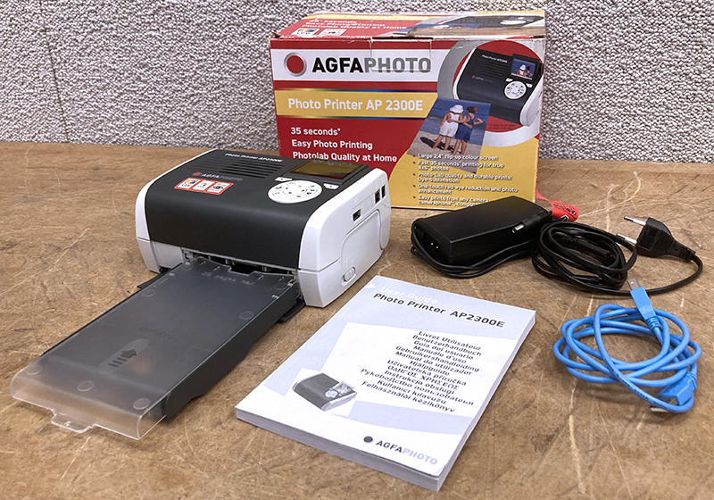 IMPRIMANTE A PHOTOS PORTABLE DE MARQUE AGFA PHOTO MODELE PHOTO PRINTER AP2300E DARKGREY AVEC SON ALIMENTATION, 1 CABLE USB, SON MODE D'EMPLOI ET 1 BAC A PAPIER. DANS SON EMBALLAGE D'ORIGINE.