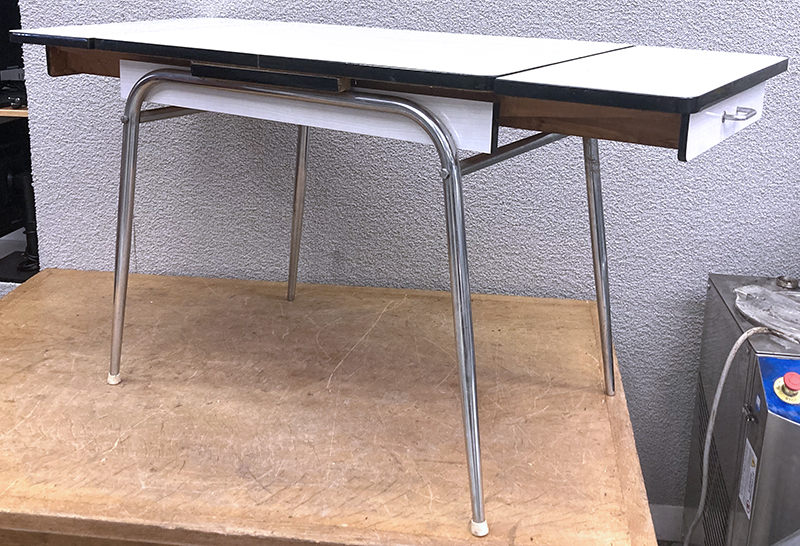 TABLE A 2 RALLONGES ANNEES 1960 A PLATEAU RECTANGULAIRE EN FORMICA DE COULEUR BLANC ET 2 TIROIRS EN CEINTURE REPOSANT SUR UNE STRUCTURE EN ACIER CHROME A 4 PIEDS. MANQUE 2 PATINS. DIMENSIONS MINIMALES : 74,5 X 90 X 60 CM. DIMENSIONS MAXIMALES : 74,5 X 147 X 60 CM.