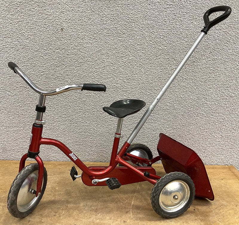 TRICYCLE A PEDALE DE MARQUE JUDEZ JOCKEY EN ACIER LAQUE ROUGE METALLISE AVEC BENNE BASCULANTE ET PERCHE D'ASSISTANCE A LA CONDUITE. 90 X 94 X 43 CM.