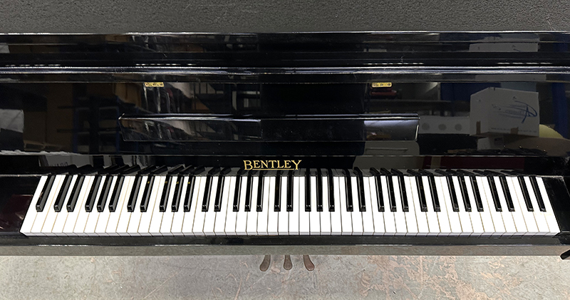 PIANO DROIT CADRE EN ACIER HABILLAGE EN BOIS LAQUE DE COULEUR NOIR DE MARQUE BENTLEY FABRIQUE EN ANGLETERRE CIRCA 1970. VENDU AVEC PROTEGE CLAVIER EN TISSUS. LOQUET DE VERROUILLAGE DE LA TRAPPE INFERIEURE HS. 98.5 X 139 X 54 CM.